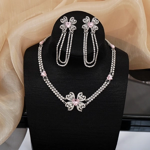 Macro detail of silver necklace and earrings set with pink heart rhinestones