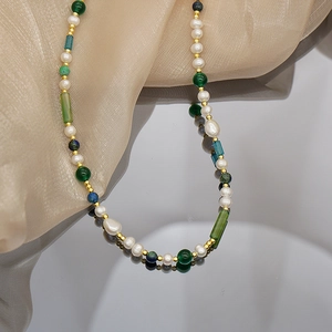 Detalle de collar con perlas de agua dulce y ágata verde sobre seda brillante