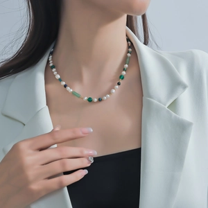 Vista detallada del collar artesanal con perlas de agua dulce y piedras verdes en la modelo