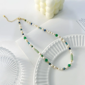 Detalle de collar de perlas y ágata verde en un plato de cerámica blanca
