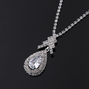 Detailed view of silver tennis chain with pear-shaped teardrop zircon pendant on black mirror