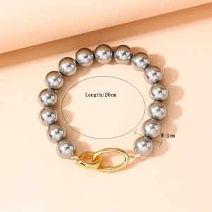 Détail macro du bracelet en perles grises de 1cm avec fermoir ovale doré entrelacé