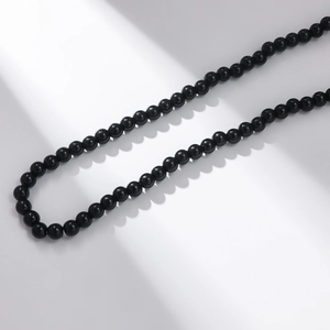 Macro detail of glossy black crystal beads necklace with high reflection on white backdrop