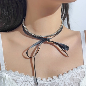 Close-up of metallic beads and black ribbon bow choker necklace on a female neck