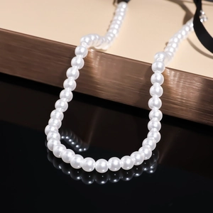 Detailed view of elegant white beaded flower necklace with black ribbon on metal stand