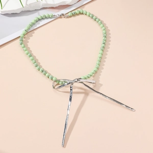 Détail du collier choker en perles turquoise avec un pendentif nœud en métal argenté