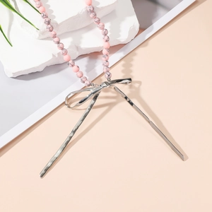 Détail des perles en marbre rose et du pendentif nœud en métal argenté avec texture martelée