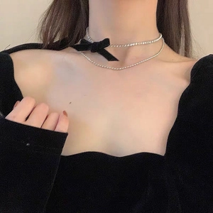 Detalle de gargantilla de doble capa con lazo de terciopelo negro y cadena de strass brillante