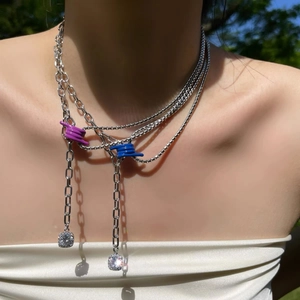 Detail of silver layered chain necklace with colorful knotted accents and zircon pendants