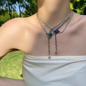 Detail of layered silver chain necklace with blue green knots and zircon pendants