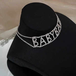 Collier ras du cou argenté élégant avec lettres BABY en strass brillants sur modèle noir