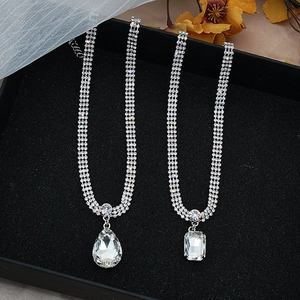 Detalle del collar plateado con colgantes de cristal cuadrados y de lágrima sobre terciopelo