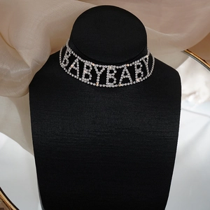 Détail macro du collier choker argenté orné de lettres BABY étincelantes en strass