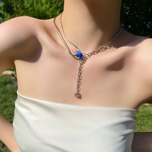 Double layered silver necklace with blue knot charm and clear zircon pendant on model