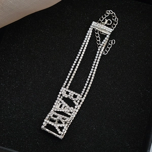 Détail macro d'un ras de cou argenté avec lettres DIOR en cristal sur boîte à bijoux