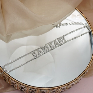 Détail du collier choker BABYBABY argenté avec strass sur un tissu en satin