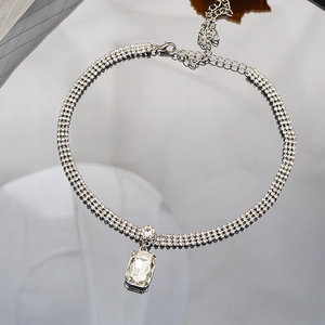 Detalle de gargantilla de cristal plateado con tres filas de pedrería y colgante cuadrado