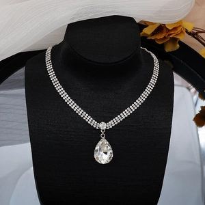 Primer plano de collar de plata con triple fila de pedrería y colgante de cristal en lágrima