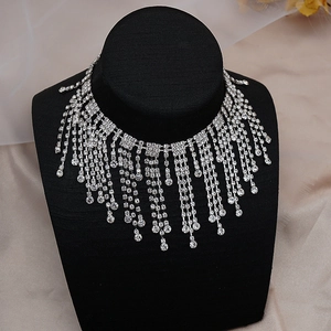 Gros plan détaillé d'un collier ras du cou argenté à pompons strass sur support en velours
