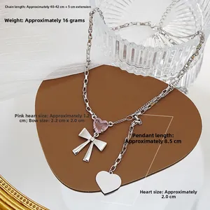 Detalle del colgante de corazón de cristal rosa con lazo plateado y medidas