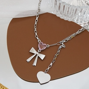 Collar con corazón de cristal rosa y lazo plateado en elegante soporte de terciopelo