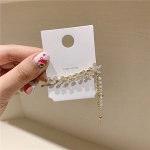 Détail d'une pince à cheveux feuille avec cristaux, pompons et perles sur carte