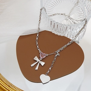 Detalle de piedra de corazón rosa y colgante de lazo plateado en collar de cadena box