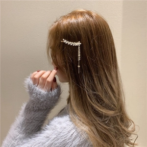 Détail de la barrette dorée en forme de feuille avec strass et longue pampille de cœur