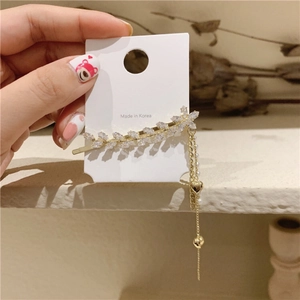 Vue détaillée de la pince à cheveux dorée en forme de feuille avec cristaux et pompons