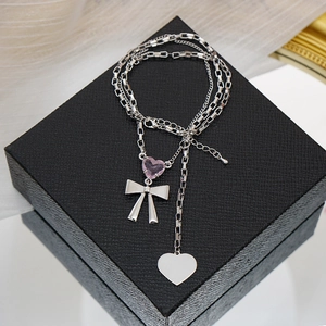 Detalle de gema de corazón rosa y colgante de lazo plateado en collar pulido