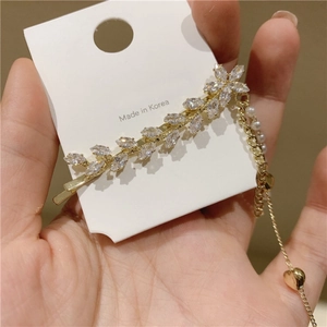 Détail de la pince à cheveux feuille en strass avec pompon perle et cœur