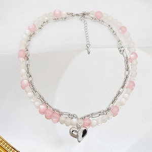 Gros plan détaillé d'un collier à deux rangs de perles avec pendentif cœur sur soie blanche