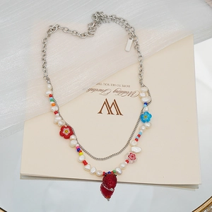 Détail d'un collier double rang avec pendentif fraise en résine, perles et perles fleuries