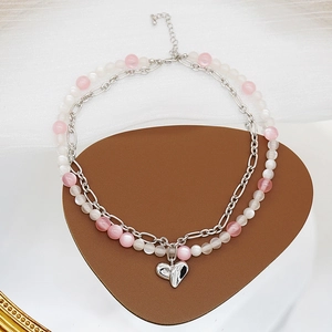 Détail d'un collier double épaisseur avec pendentif cœur argenté et perles roses