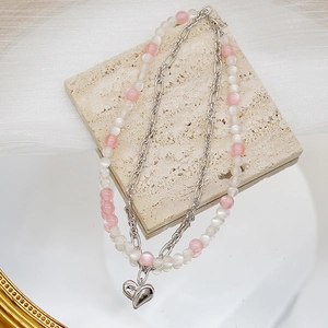 Gros plan du collier double couche avec perles roses et pendentif cœur en argent