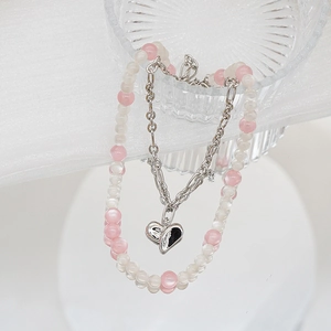 Détail du collier double couche en perles roses et blanches avec pendentif coeur