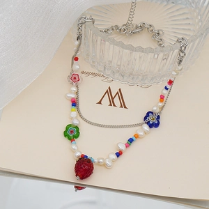 Détail d'un collier de perles fait main avec perles baroques et pendentif fraise en résine