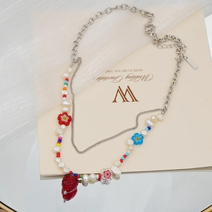 Gros plan du pendentif fraise et perles baroques sur un collier de perles multicouche