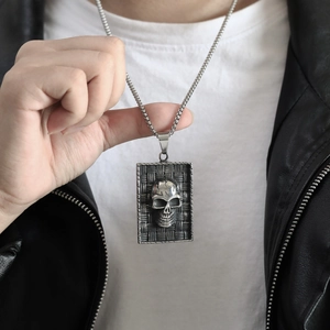 Détail d'un pendentif crâne vintage sur chaîne gourmette avec une veste en cuir noir