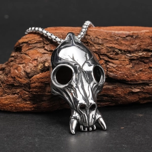 Macro view of a silver predator skull pendant with sharp tusks on rustic tree bark