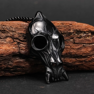 Macro shot of a polished black animal skull pendant with beaded chain on tree bark