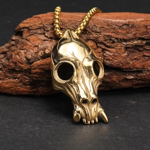 Polished gold animal skull pendant necklace for men with a box chain on tree bark