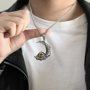 Detailaufnahme von Halbmond und goldenem Totenkopf Anhänger an einer Viereck-Gliederkette