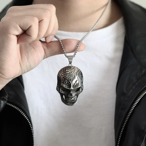 Primer plano de un colgante de calavera punk en plata vieja con cadena de caja