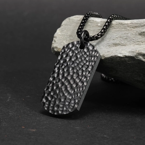 Collana da uomo con piastrina in titanio nero opaco e texture martellata su una pietra