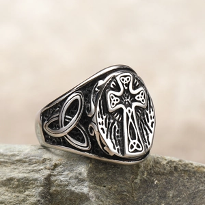 Macro detail of vintage stainless steel Celtic cross ring with triquetra knot on rock