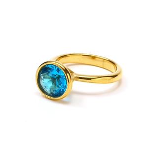 Detailed close-up of a 18k gold-plated titanium ring with a large round blue zircon stone