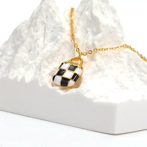 Ketting met dambordhanger en gouden ketting op een wit stenen beeldhouwwerk