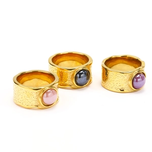 Macro shot of three chunky gold rings with irregular foil texture and ceramic cabochons