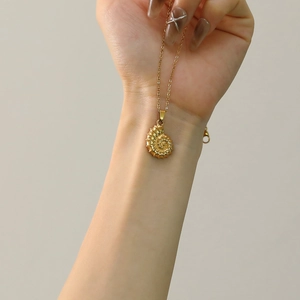 Macro-opname van de 18k gouden schelphanger met fijne spiraalvormige texturen en details